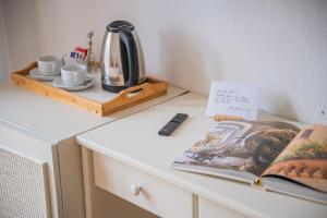 a tea kettle and cups and a book on a dresser at Casa Pertosa in Taormina