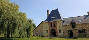 an old brick house with a roof and trees at Les Bucoliques de la Noë in Goven