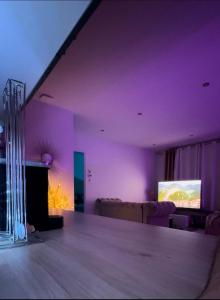 a purple living room with a couch and a tv at Paris Giverny familles & professionnels in Freneuse