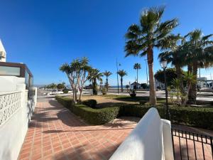 a walkway with palm trees and a fence at Casa de playa los Alamos Andra in Torremolinos