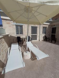 a patio with white chairs and an umbrella at The center of Crete in Ayía Varvára