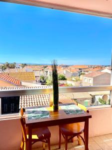 a table and chairs on a balcony with a large window at Studio 100m de la mer et port in Valras-Plage +6 photos