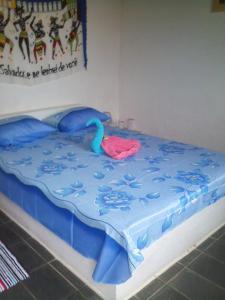 a bed with a blue blanket and an infront at Pousada Ancora in Vera Cruz de Itaparica