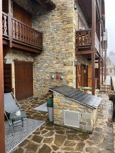 ein Steingebäude mit einem Steingrill auf einer Terrasse in der Unterkunft Charme et confort au pied des pistes in Naut Aran