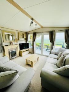 ein Wohnzimmer mit Sofas, einem TV und einem Tisch in der Unterkunft Holiday Home with Stunning Views in Newquay