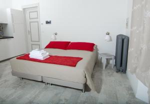 a white bedroom with a bed with red pillows at A Casa di Lu Na in Bologna