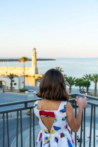 a young girl in a dress looking at the ocean at V77 Seafront Suites in Rethymno