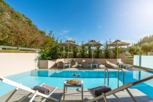 a swimming pool with chairs and umbrellas in a house at Aria Luxury Residence in Syvota