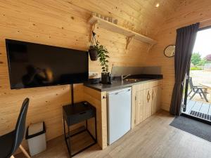 a kitchen in a log cabin with a large flat screen tv at Woodlodge de luxe 2 persoons in Oorsbeek