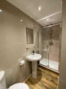 a bathroom with a sink and a shower and a toilet at The Upton Coach House in Birkenhead +16 photos