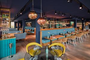 a restaurant with blue walls and yellow chairs and tables at New Wave in Norderney