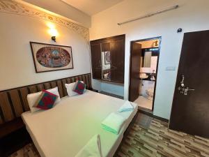 a bedroom with a large white bed and a bathroom at Max Guest House in Agra