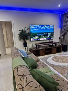 17 Santana Pebbles Penthouse في لا ميرسي: غرفة معيشة مع أريكة وتلفزيون بشاشة مسطحة