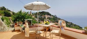 einen Balkon mit einem Sonnenschirm, einem Tisch und Stühlen in der Unterkunft RACHELE HOUSE in Amalfi