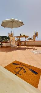 ein Teppich auf einer Terrasse mit Stühlen und einem Sonnenschirm in der Unterkunft RACHELE HOUSE in Amalfi