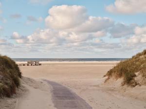 einen Sandstrand mit einer Straße zum Meer in der Unterkunft New Wave in Norderney
