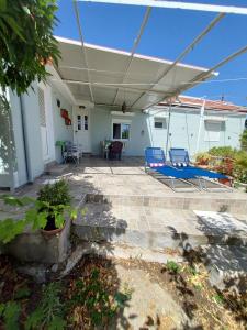 a patio with blue lounge chairs and an umbrella at Anastasia's holiday house with garden in Ialysos