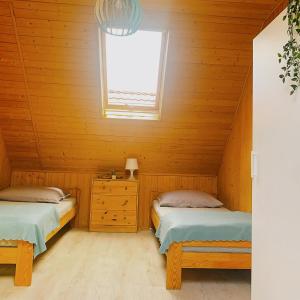 two beds in a wooden room with a window at Domek letniskowy Magda in Łeba