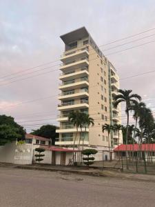 a tall white building with palm trees in front of it at Suite 6 per Tonsupa Edf Tritón in Tonsupa