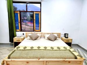 1 dormitorio con 1 cama de madera y 2 ventanas en Apna Ghar - Bir, en Bīr
