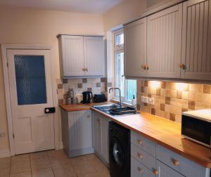 a kitchen with white cabinets and a sink and a dishwasher at Number 9 in Hunstanton