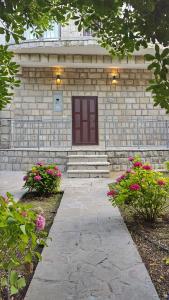 a stone building with a brown door and some flowers at Villa Sazanka with private pool in Kamenari