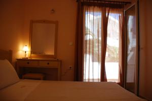 a bedroom with a bed and a mirror and a window at Fyri Ammos Residences in Agia Pelagia