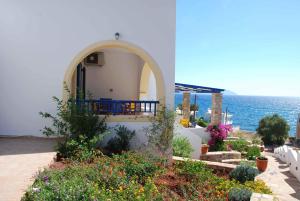 a white building with a balcony and the ocean at Fyri Ammos Residences in Agia Pelagia