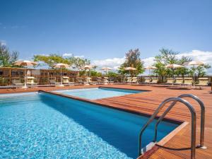 a swimming pool with tables and chairs and umbrellas at Club del Sole Milano Marittima Boutique Resort in Milano Marittima