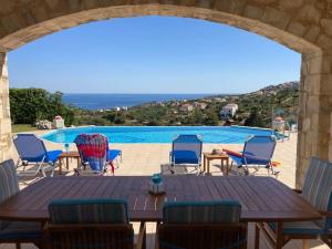 a patio with a table and chairs and a pool at Villa Thea,Plaka with sea & mountain views in Kambiá