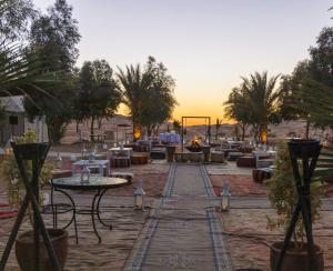 a patio with tables and chairs and a fire place at Merzouga Stars Luxury Camp in Merzouga