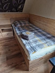a small bed in a room with wooden floors at Agroturystyka Ruta nad zalewem Siemianówka in Łuka