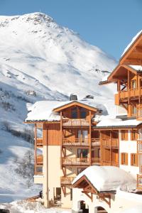 a resort with snow covered mountains in the background at Le Chalet du Mont Vallon Spa Resort in Les Menuires