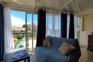 a blue couch in a living room with a large window at Pavillon d'Urs in Fleury