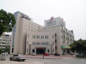 een groot wit gebouw met auto's geparkeerd voor het bij Jinjiang Inn Changshu Yushan in Changshu