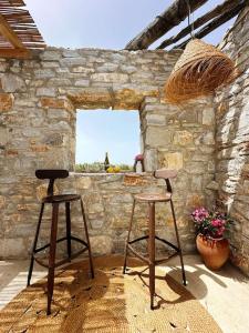two stools in front of a stone wall with a window at Μονοπάτι in Agia Anna Naxos +20 photos