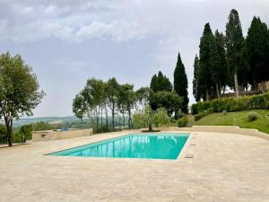 a swimming pool in a yard with trees and a hill at Casina di Adele apartment in Volterra