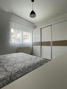 a white bedroom with a bed and a window at Entire Apartment - near the Center in Pristina