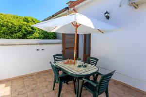 un tavolo con ombrellone bianco su un patio di Villa Alimini - Villetta con veranda Laghi Alimini a Otranto