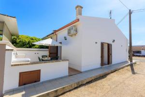 un edificio bianco con un tavolo e un ombrellone di Villa Alimini - Villetta con veranda Laghi Alimini a Otranto