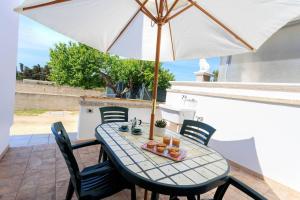 un tavolo con un ombrellone in un patio di Villa Alimini - Villetta con veranda Laghi Alimini a Otranto
