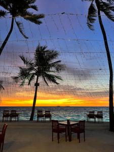 a table and chairs on the beach with a sunset at Heron Beach Hotel - The Best Maldivian Getaway in Dhiffushi,Maldives in Dhiffushi