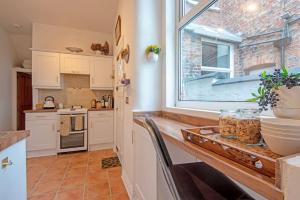 una cocina con armarios blancos, una ventana y una encimera en Stylish Town House, en Sale 15 fotos más
