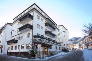 a white building with balconies on a snowy street at Hotel Sporting in Roccaraso