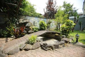 a garden with a stone wall and a brick walkway at Green House Hotel in Kobuleti