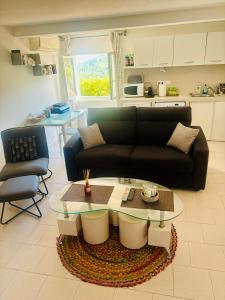 a living room with a black couch and a table at Appartement Calme entre mer, montagne et rivière in Conca