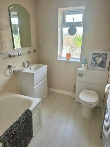 a bathroom with a sink and a toilet and a mirror at 1min walk to Beach- Happy Waves- Family Home in Camber