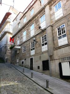 a large stone building with white windows on a street at Hostal Continental in Vigo