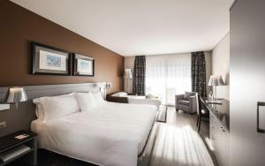 ein Hotelzimmer mit einem weißen Bett und einem Stuhl in der Unterkunft Hotel Belvedere Locarno in Locarno