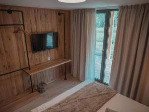 a bedroom with a bed and a tv and a window at Vama Chalet in Vama Buzăului
